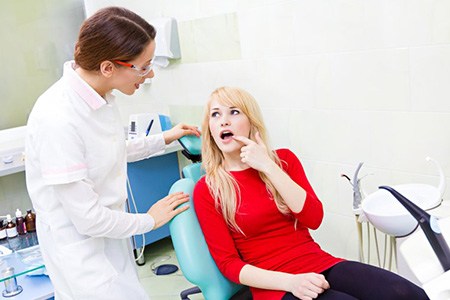 Dentist and patient discussing the patient’s toothache as she points 
